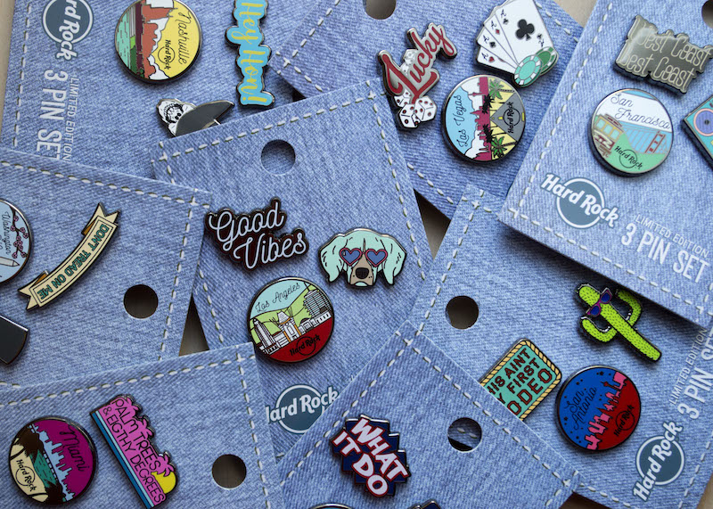 A scattered pile of enamel pins on backing cards. 