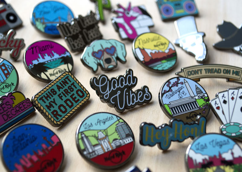 Several enamel pins laid out on a hard surface. 